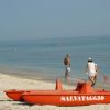 Una spiaggia con un'imbarcazione arancione per il salvataggio e persone che camminano lungo la riva.