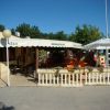 Area esterna minimarket con tenda bianca, tavoli arancioni sotto gazebo.