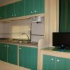 Cucina con mobili verdi, lavello e televisore piccolo.