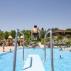 Persona salta dal trampolino in piscina affollata.