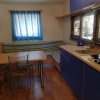 Una cucina con tavolo e sedie, tendine blu, divanetto a righe.
