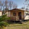 Casetta di legno beige con veranda in giardino.