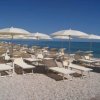 Una spiaggia con sedie a sdraio e ombrelloni bianchi.