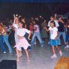 Gruppo di persone che ballano in un ambiente coperto, tra cui bambini e adolescenti.