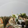 Spiaggia con ombrelloni, palme e arcobaleno.