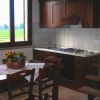 Cucina rustica con tavolo in legno, cestino di fiori e finestra aperta su un panorama verde.