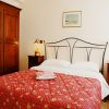 Camera con letto matrimoniale, copriletto rosso, comodini e armadio in legno.