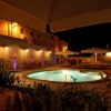 Piscina notturna con ombrelloni e mura in mattoni.