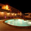 Piscina illuminata di notte accanto a un edificio in mattoni.