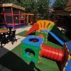 Parco giochi con scivolo colorato, tunnel e tavolino con sedie.