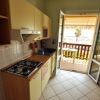 Una cucina con mobili chiari, piano cottura a gas e porta-finestra aperta sul balcone.