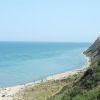 Una spiaggia con mare blu e colline verdi.