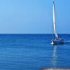 Una barca a vela bianca solca il mare blu sotto un cielo limpido.