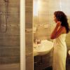 Una donna avvolta in un asciugamano si guarda nello specchio di un bagno moderno con doccia.