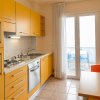 Cucina con mobili gialli e accesso al balcone.