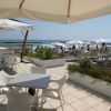 Terrazza esterna con tavoli sotto ombrelloni, vista mare e lettini sulla spiaggia.