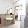 Bagno moderno con doccia a pioggia, specchio e portasciugamani con asciugamani rossi.