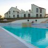 Piscina con sdraio e ombrelloni, davanti a edifici moderni all'alba o al tramonto.