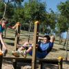 Due persone si allenano su attrezzature all'aria aperta in un parco alberato.