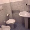Bagno con sanitari, lavabo su piede, piastrelle quadrate grigie su pavimento e pareti.