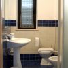 Bagno con lavabo, wc e finestra con tenda a rullo.