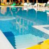 Dettaglio della piscina con scalini bianchi, riflessi nitidi e lettini gialli, immersa nel sole.