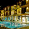 Hotel illuminato di notte con piscina e lettini all'aperto.