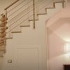 Scala moderna con ringhiera metallica e lampada da tavolo accesa su una credenza.