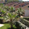 Complesso di villette con tetti arcuati, palme e giardino.