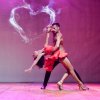 Coppia balla sul palco, sfondo a forma di cuore.