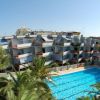 Complesso di appartamenti moderni con una grande piscina circondata da palme.