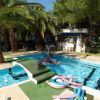Piccola piscina con area giochi, circondata da palme e arbusti.