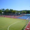 Un campo sportivo all'aperto con porte da calcio e canestri, vicino a una piscina.