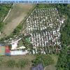 Vista aerea di un campeggio con aree verdi, campi sportivi e una piscina.